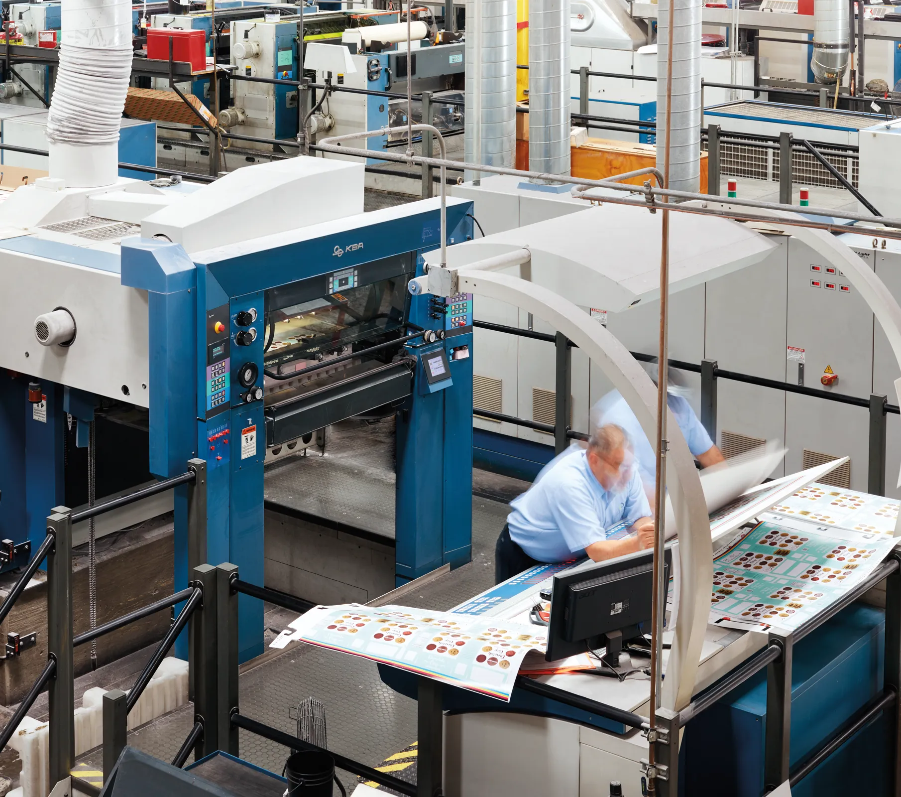 an image of a worker in an industrial setting, looking over blueprints on a desk