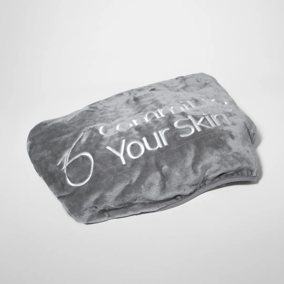 a gray throwover blanket with the words "commit your skin" on it