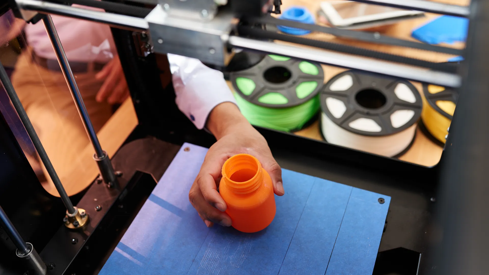 an image of a person holding an orange plastic bottle under an industrial tool