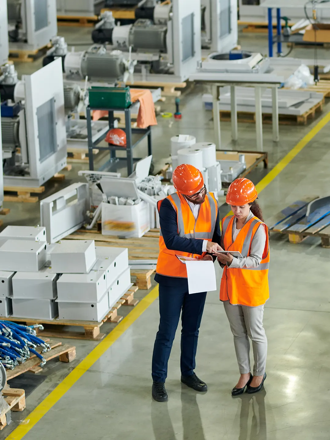 an image two workers in hard hats checking their notes in an industrial setting