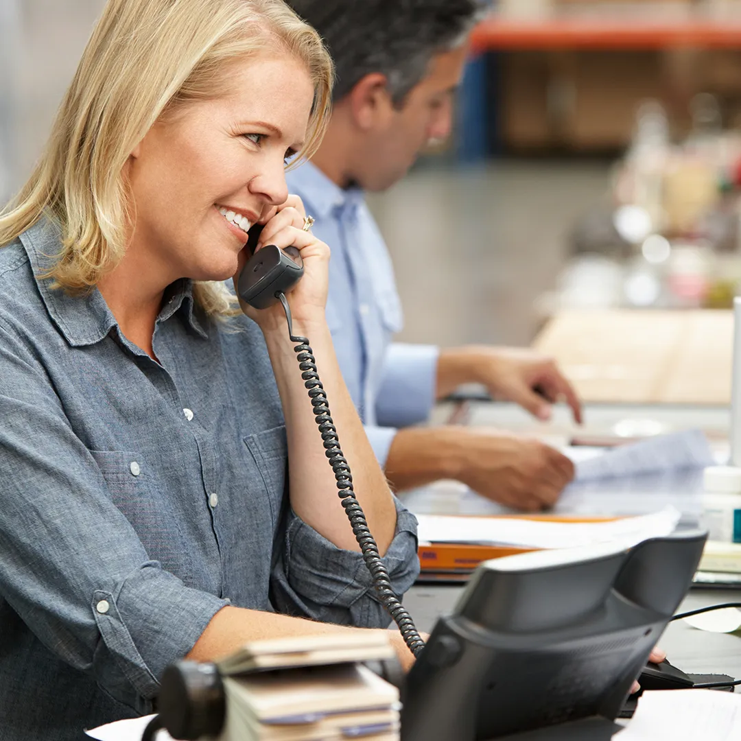 an image of two office workers next to each other, with one of them smiling while on a phone call