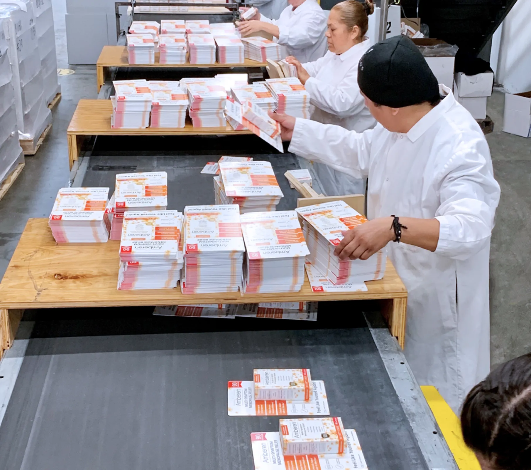 an image showing a group of workers in lab coats handling unfolded carton packaging