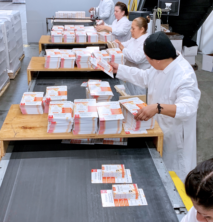 an image showing a group of workers in lab coats handling unfolded carton packaging