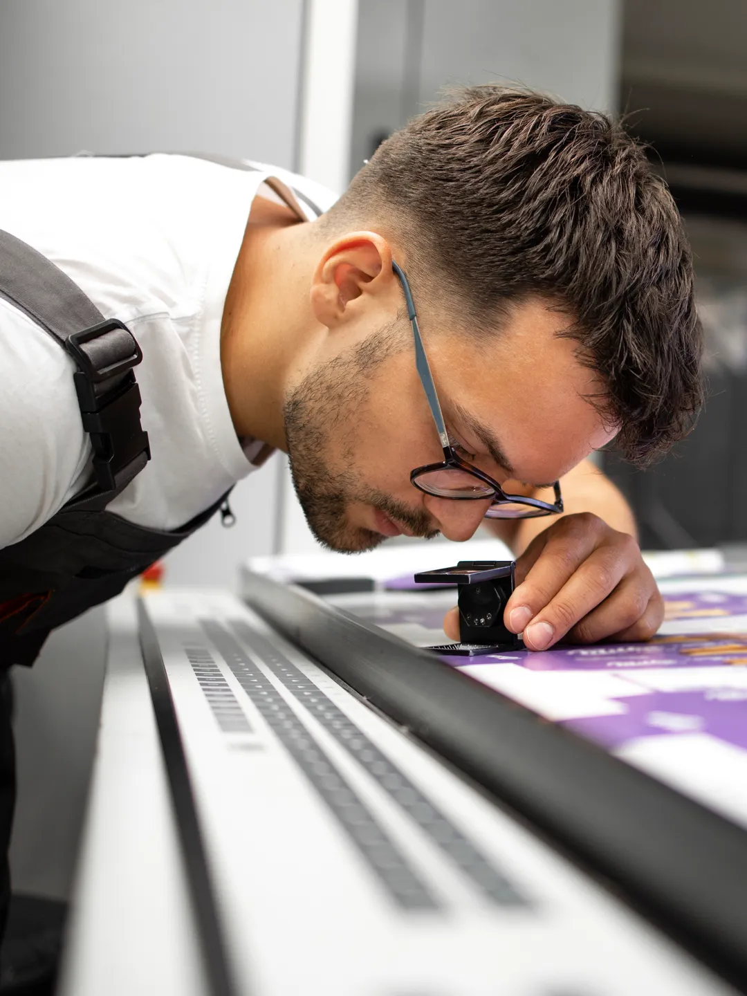 an image of a worker at an industrial workspace using a magnifying glass while looking at blueprints