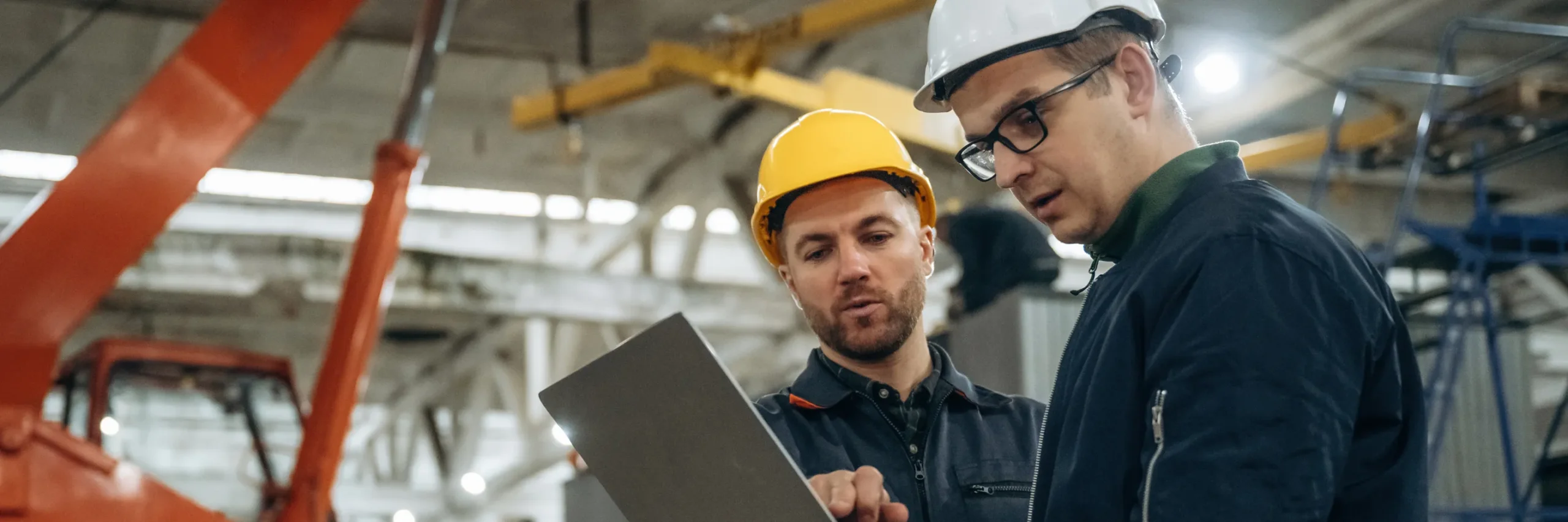 an image of two workers in a hard hat reviewing items on a tablet