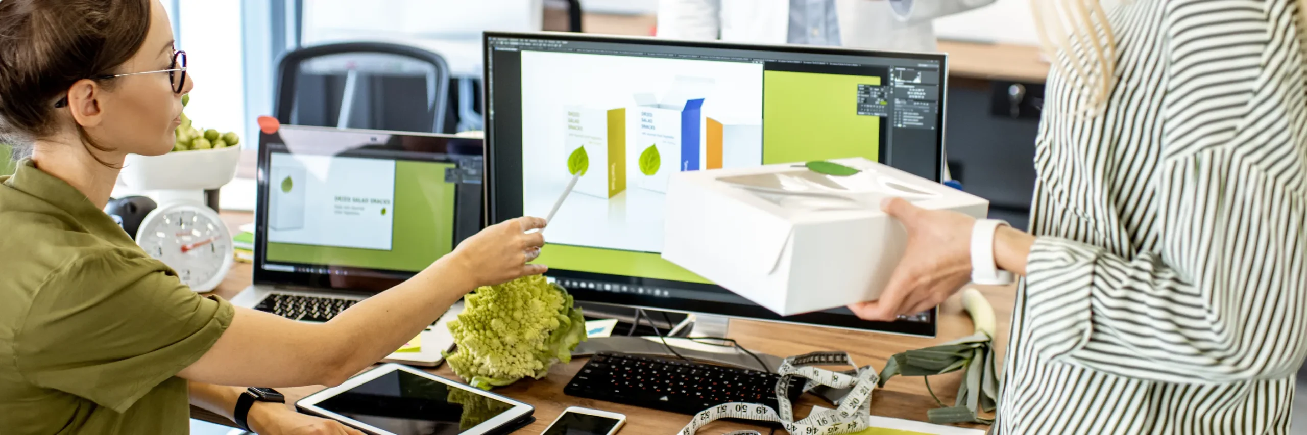 an image of two office workers with one of them pointing to something on a desktop monitor