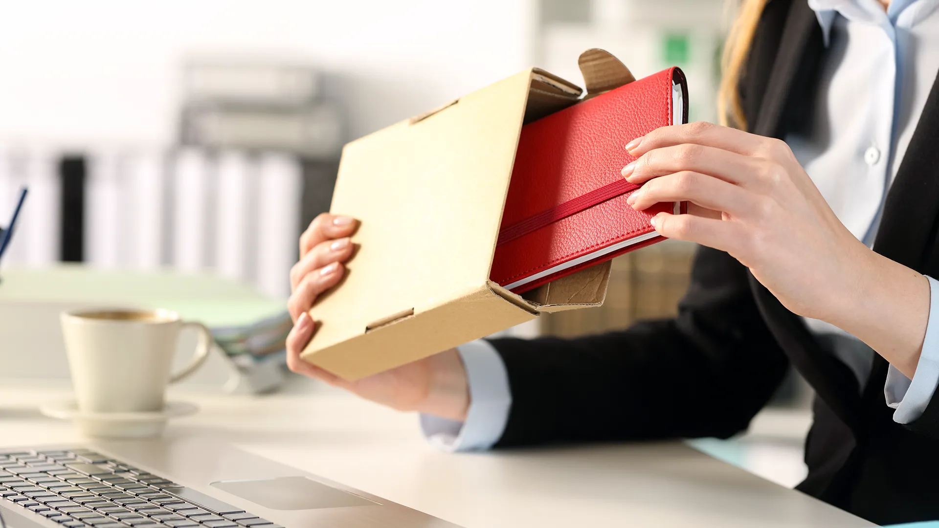 an image of a woman pulling out a journal from cardboard box packaging